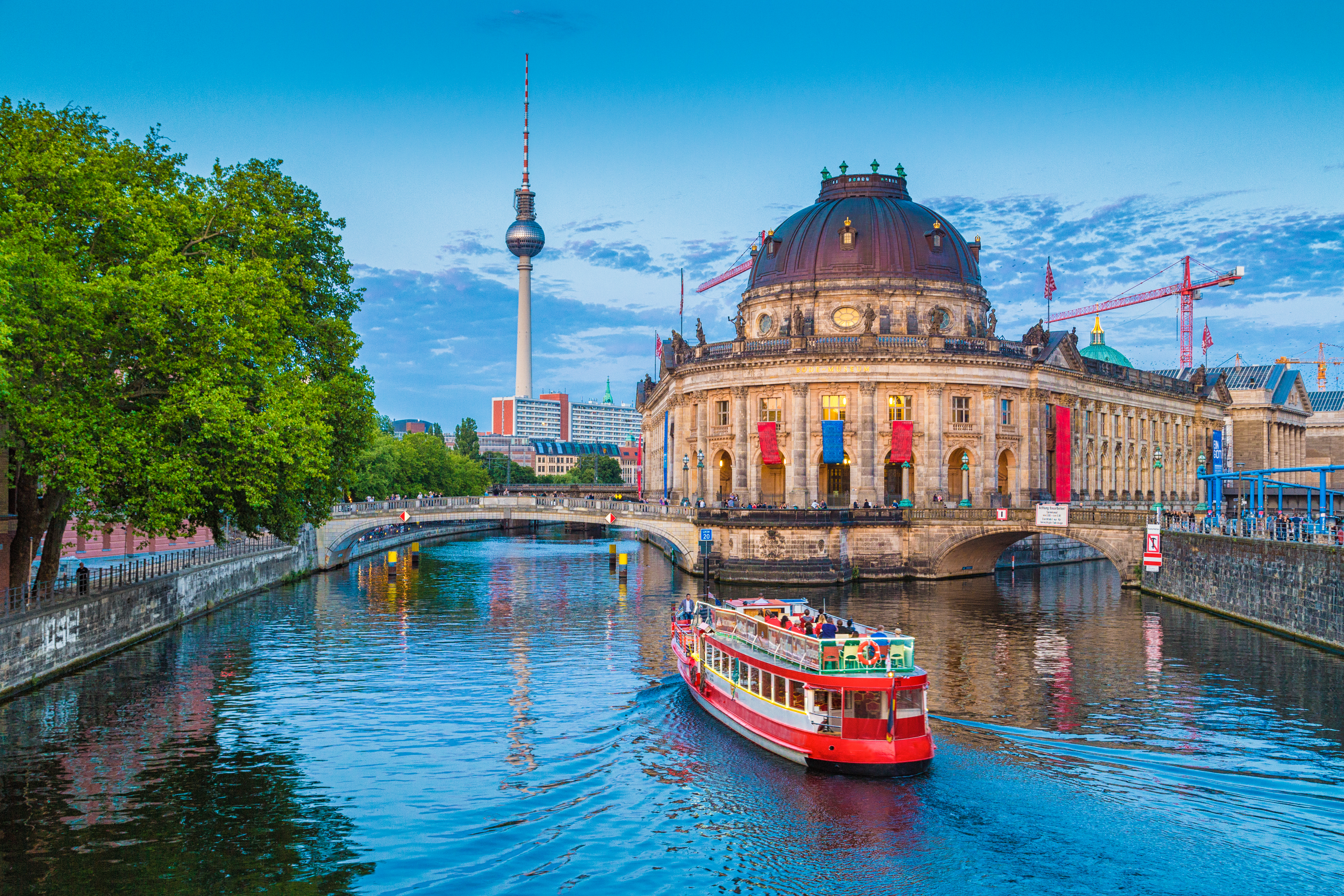 Beautiful view of UNESCO World Heritage Site Museumsinsel (Museum Island) with excursion boat on Spree river and famous TV tower in the background in beautiful evening light at sunset, Berlin, Germany